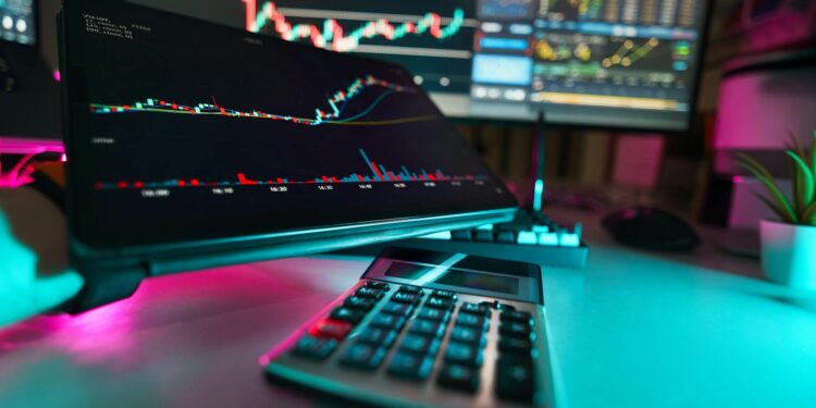 A vibrant office setup with digital tablets displaying financial analysis and stock charts, complemented by a calculator.