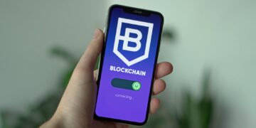 Close-up of a hand holding a smartphone with a blockchain app interface.